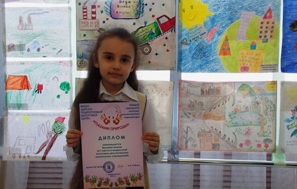 Победительница среди дошколят Амина Валиева на фоне своей работы «Я верю»